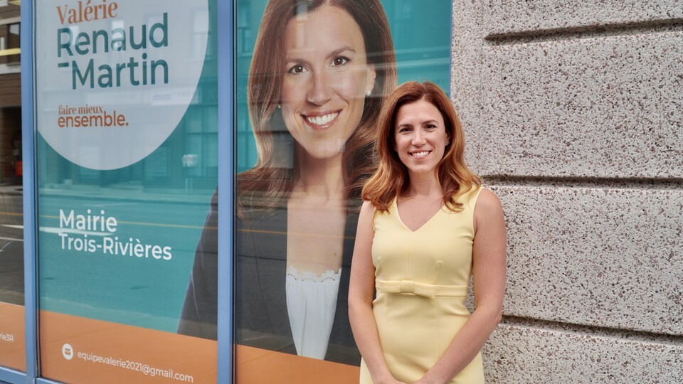 Valérie Renaud-Martin se tient devant son local de campagne électorale. Une photo d'elle est affichée dans la vitrine du local avec son slogan « Faire mieux ensemble ».