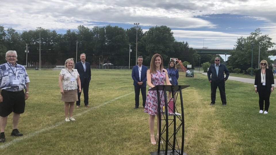 Valérie Renaud-Martin souriante devant un podium, entourée de son équipe dans un parc.