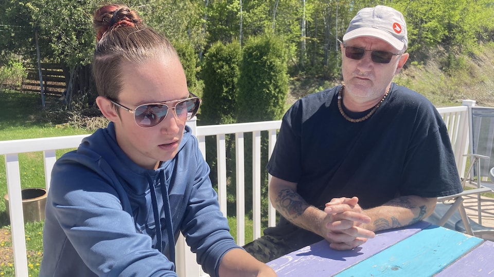 The young woman and her father were sitting at a table in their backyard on a sunny day.