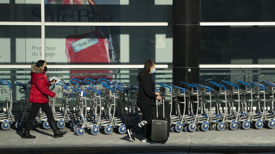 Deux femmes marchent à l'aéroport Montréal Trudeau avec leurs valises.