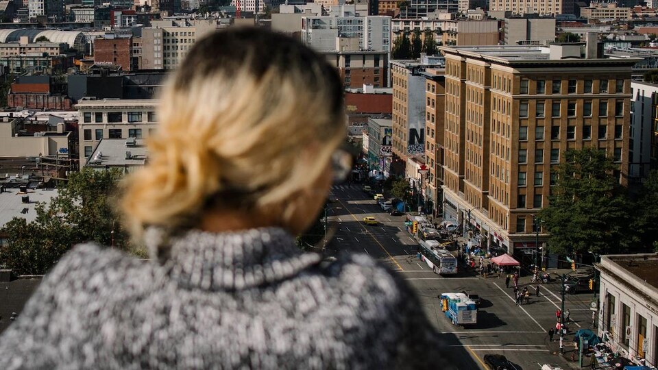 Une femme se trouve sur le toit d'un immeuble à Vancouver et regarde la rue.