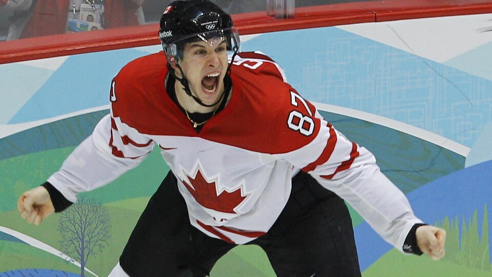Le joueur de hockey est en extase dans le coin de la patinoire après un but en prolongation aux Olympiques.