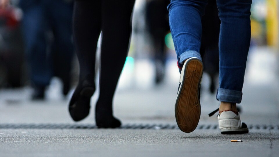 Des passants dont on ne voit que les jambes marchent dans les rues de Vancouver.