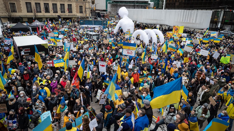 Une foule de milliers de personnes brandissant des drapeaux ukrainiens.