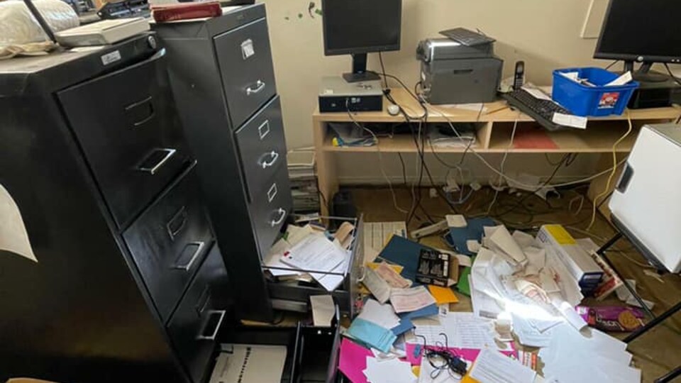 Un bureau saccagé avec des classeurs ouverts et des documents sur le sol.