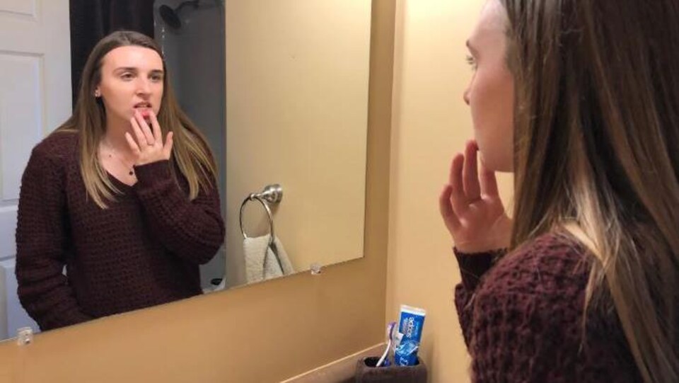 Erin se regarde dans le miroir. 