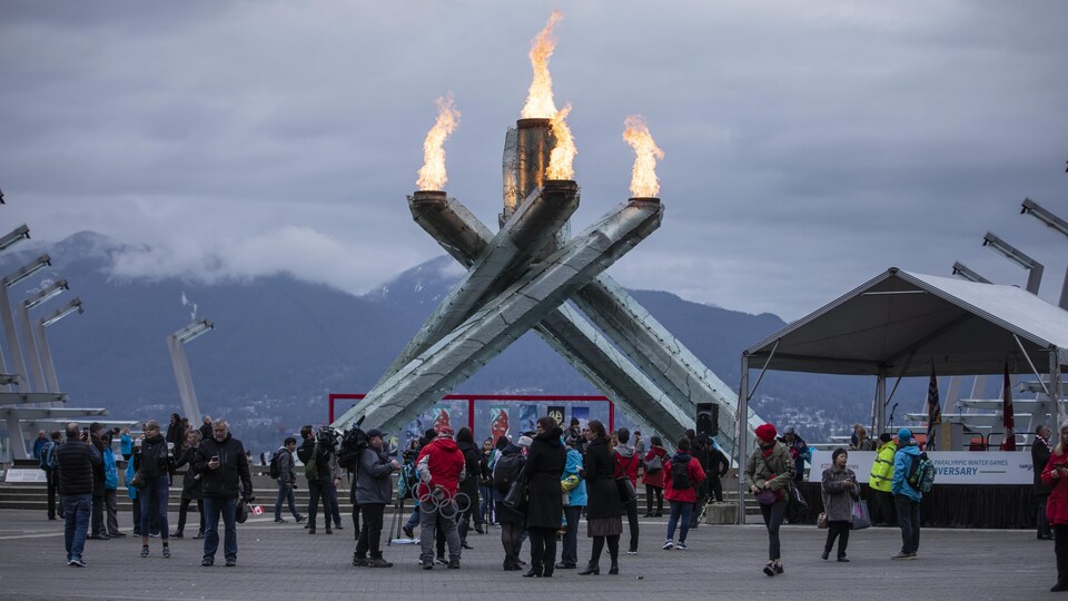 La vasque olympique allumée et des gens autour d'elle.