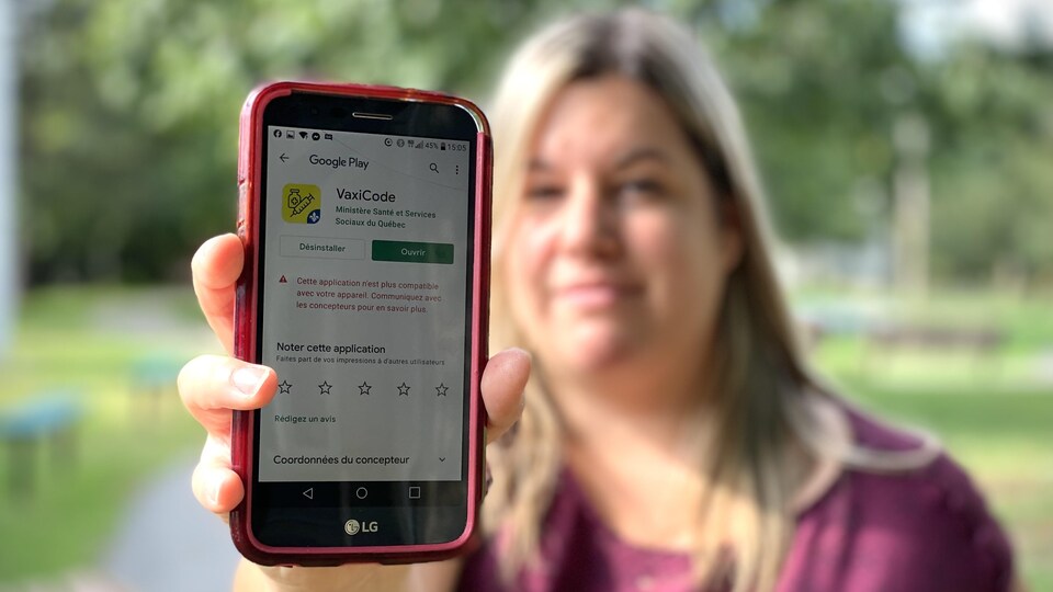 Émilie Marchand montre l'écran de son téléphone cellulaire. Une note inscrite en rouge mentionne que l'application VaxiCode n'est pas compatible avec son appareil.