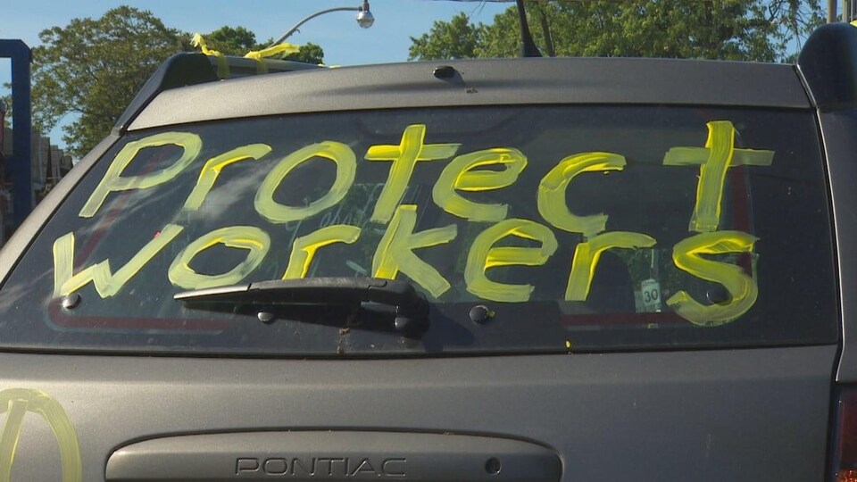 Les mots "protégez les travailleurs" en anglais sur une voiture