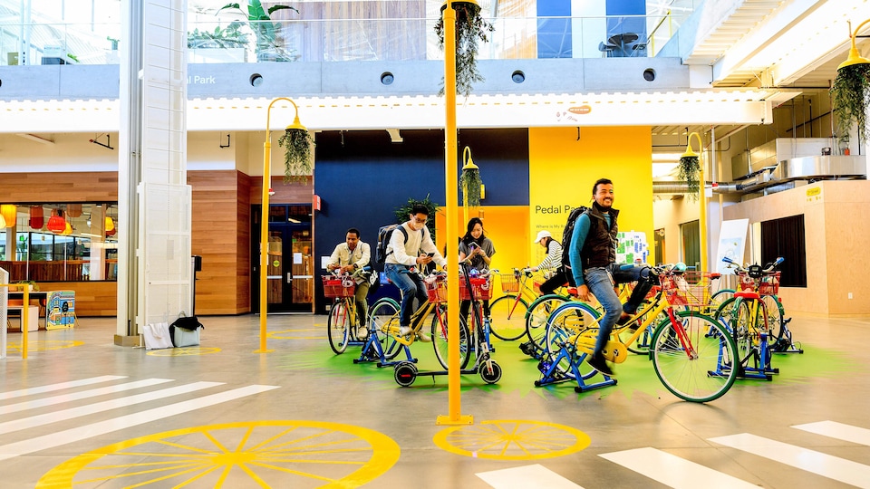 Des personnes chevauchent des vélos à l’intérieur des nouveaux bureaux de Google dans la Silicon Valley. 