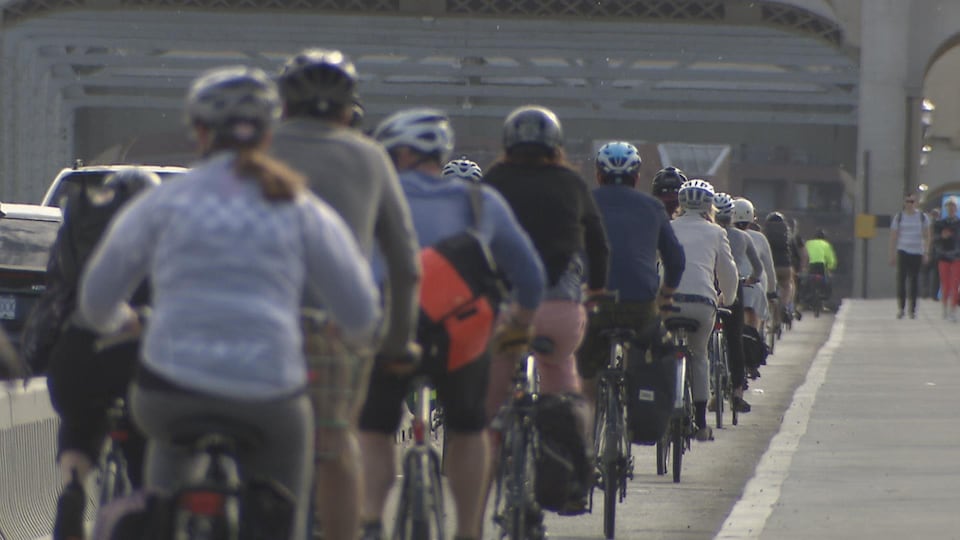 Des gens à vélo sur le pont Burrard de Vancouver un matin ensoeillé.
