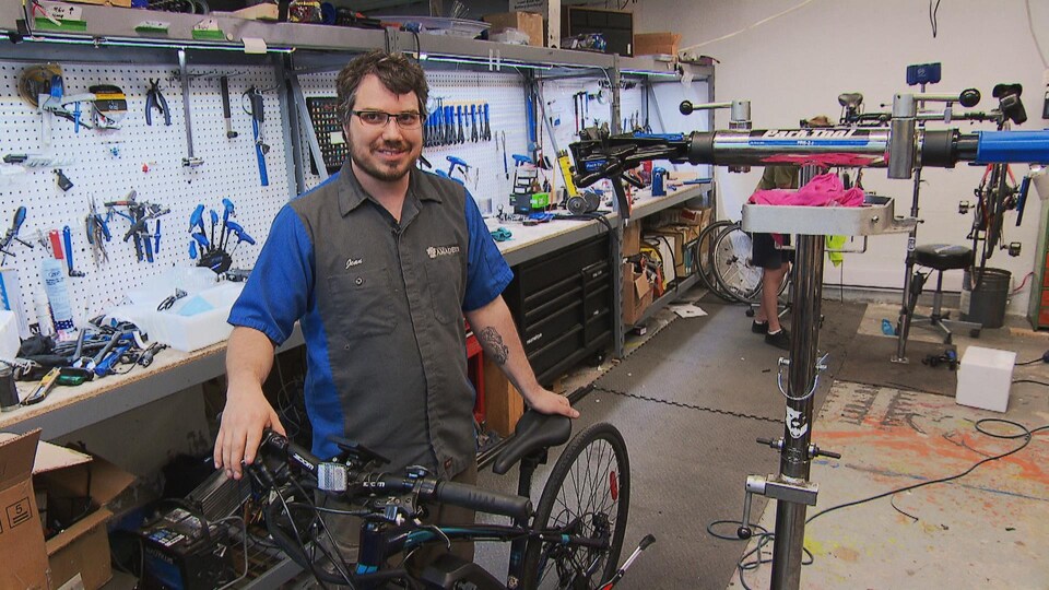 A man is holding a bicycle in a workshop.