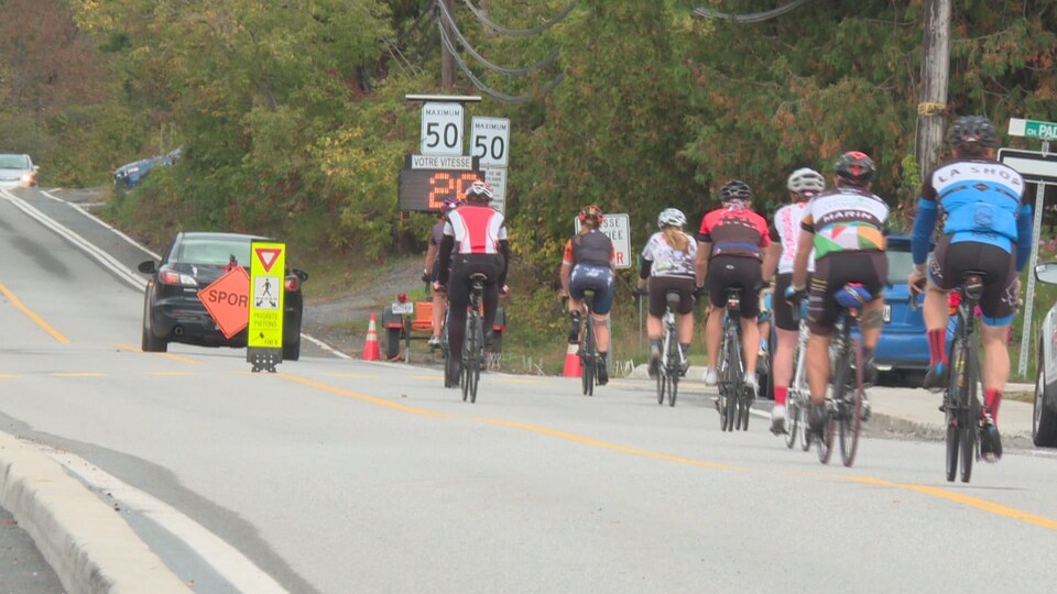 Des cyclistes roulent sur une rue avec des voitures
