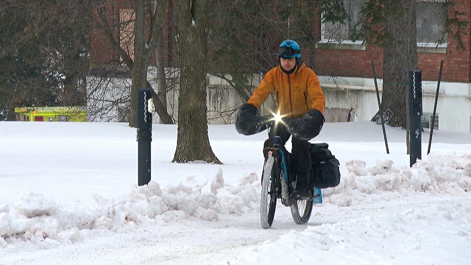 Le cycliste roule sur une piste enneigée à Gatineau.