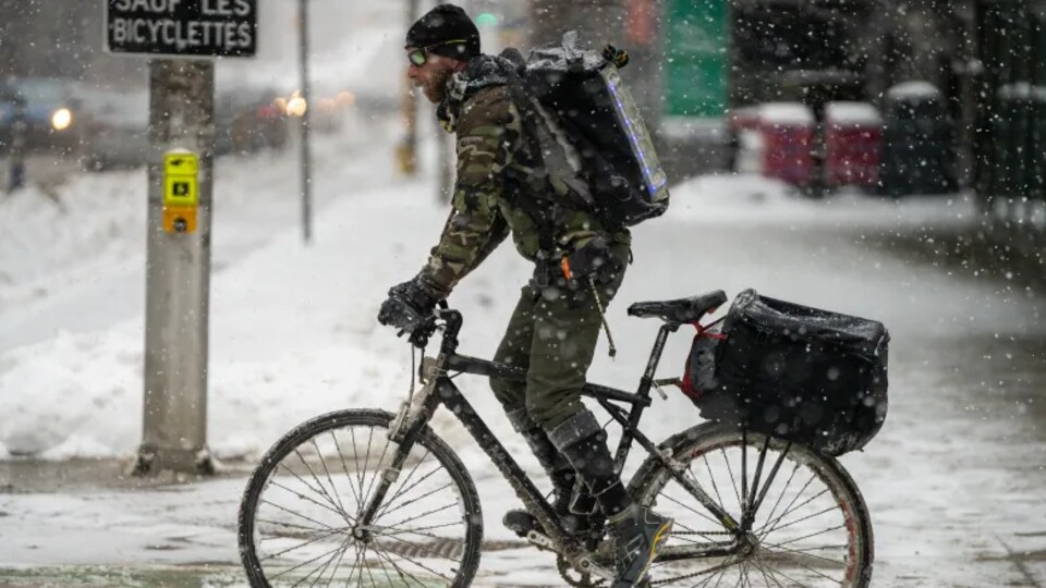 Un cycliste se promène au centre-ville en hiver.