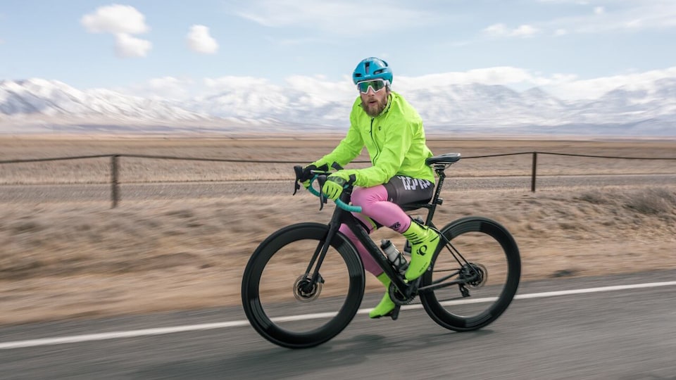 James Lawrence sur son vélo, sur une route traversant un paysage désertique de l'Utah. 