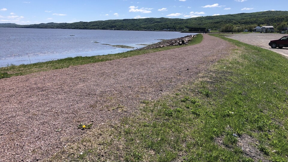 Gravel trail with water and mountains in the background.