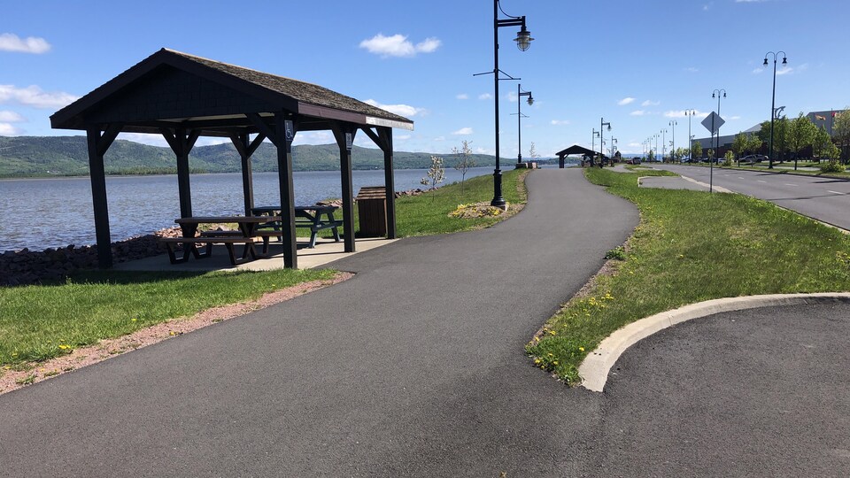 Bike path in front of the Restigouche River passing in front of a shelter.