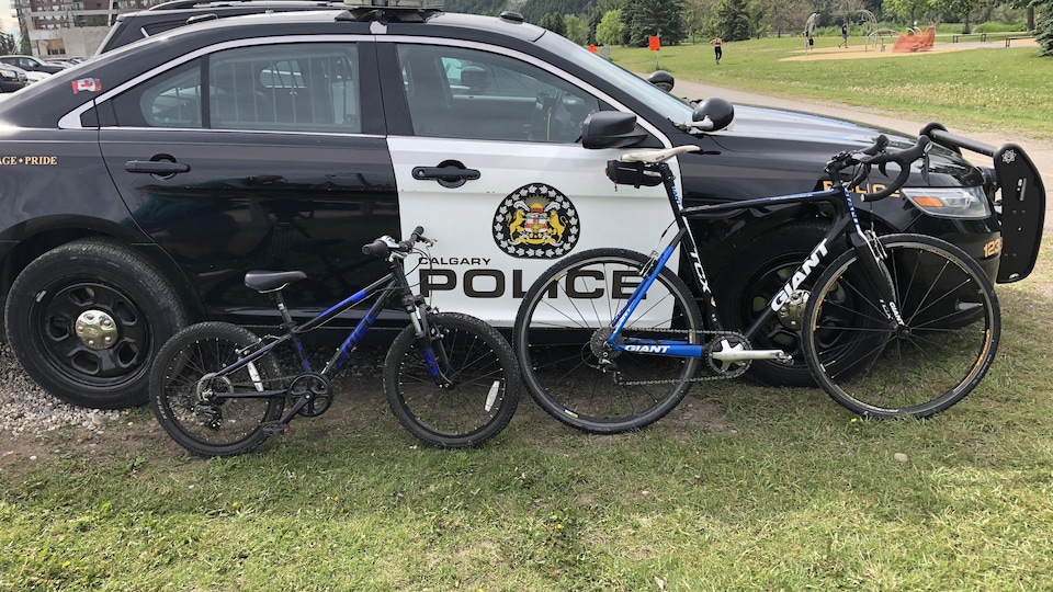Deux vélos posés contre une voiture de police.