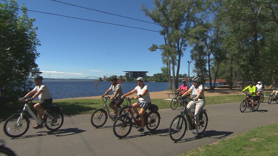 Des gens roulent à vélo sur le bord du fleuve Saint-Laurent à Trois-Rivières.