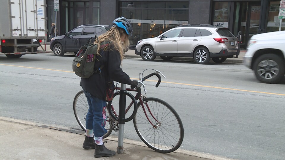 Une femme installe son vélo sur un support à vélo dans une ville urbaine. 