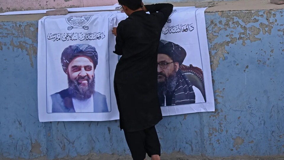 Il installe des affiches des leaders talibans Mullah Abdul Ghani Baradar et Amir Khan Muttaqi.