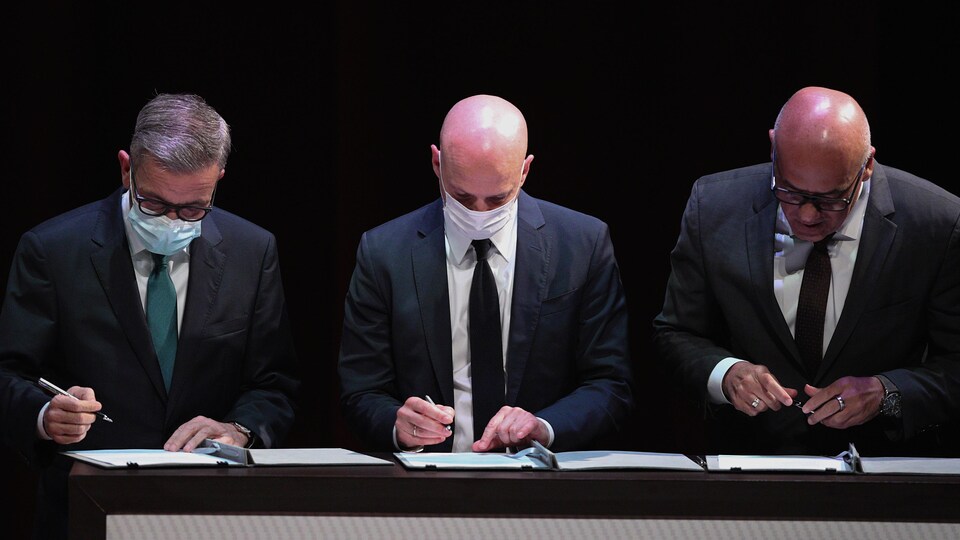 Trois hommes signant des documents