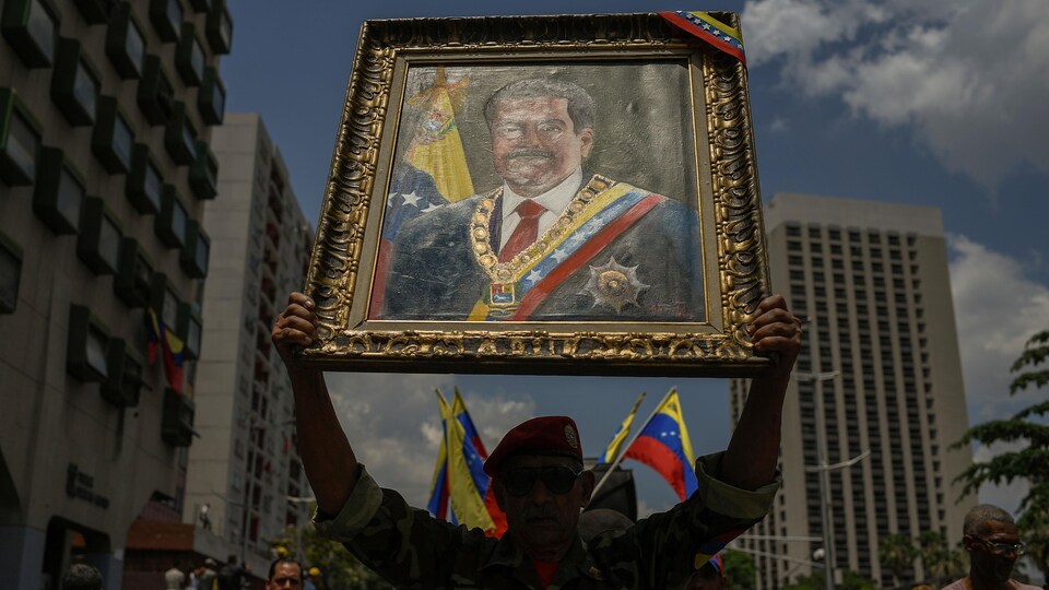 Un militaire vénézuélien brandit un portrait du président Nicolas Maduro en marchant dans une rue de Caracas.