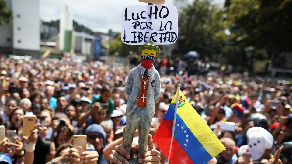 Un manifestant tient une statuette qui indique : « Je me bats pour la liberté ».