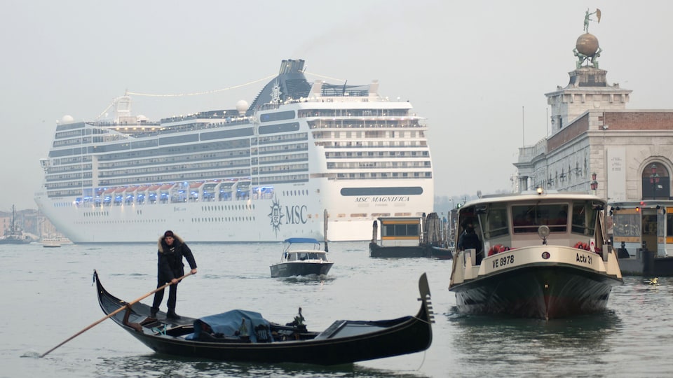 Un navire de croisière dans le Grand canal de Venise, devant un batelier sur sa petite embarcation.