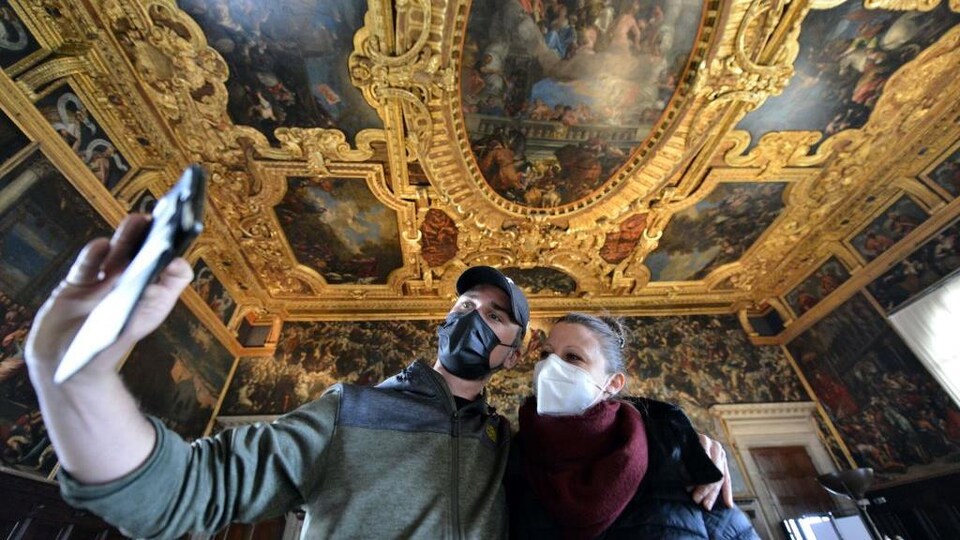 Un homme et une femme portant un masque se prennent en photo avec une téléphone cellulaire.