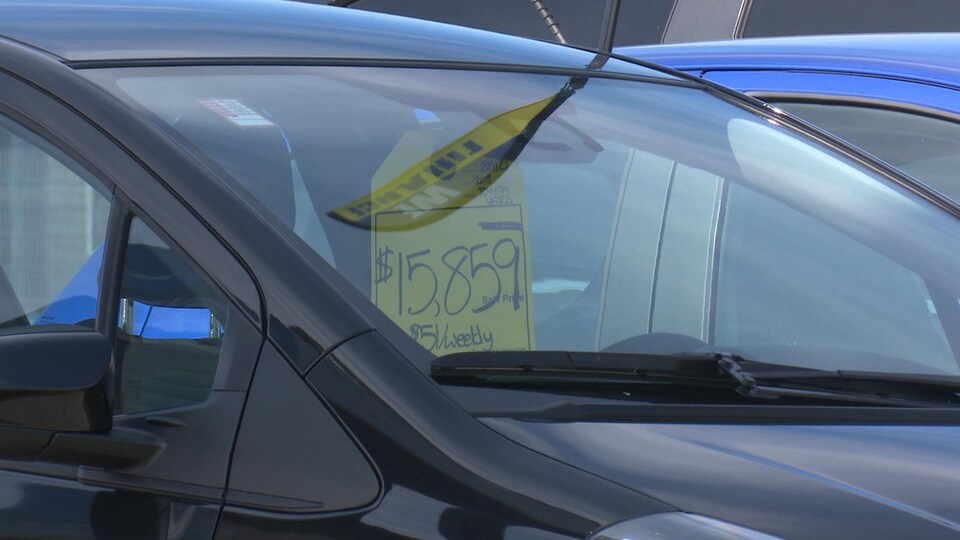 Affiche avec un prix accroché sur le rétroviseur d'une automobile.
