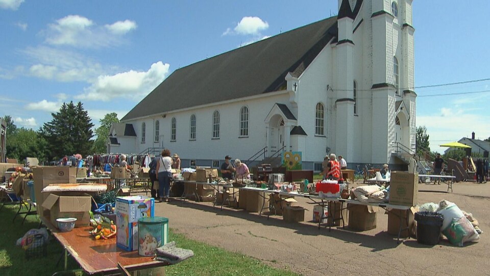 Des objets divers disposés sur des tables à l'extérieur, près d'une église.
