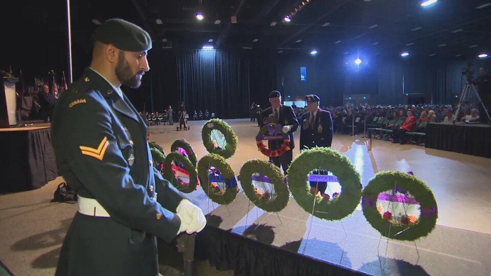 Un soldat assiste à la cérémonie du jour du Souvenir au Centre des congrès RBC à Winnipeg, alors que deux vétérans viennent déposer une couronne de fleurs au mémorial, en hommage aux combattants canadiens.