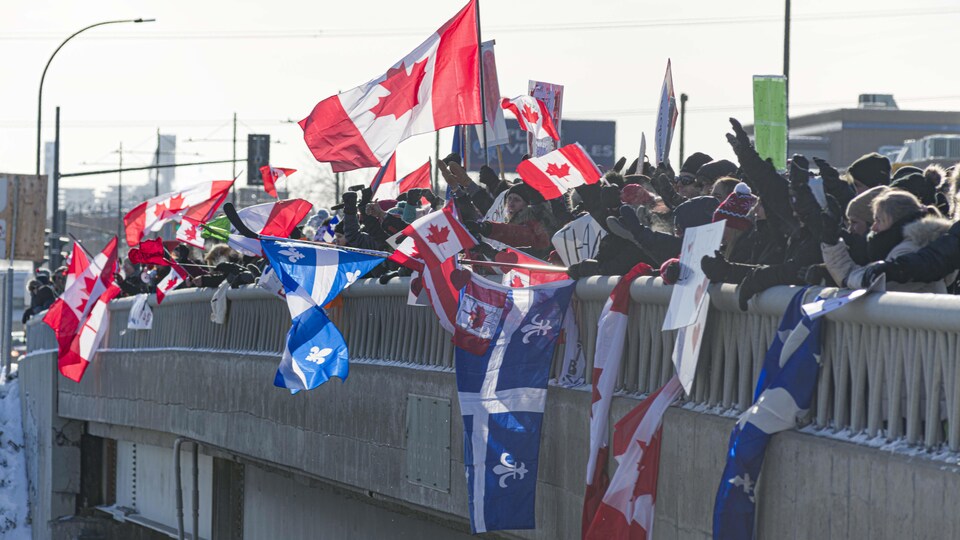 Des gens brandissent des drapeaux sur un viaduc.