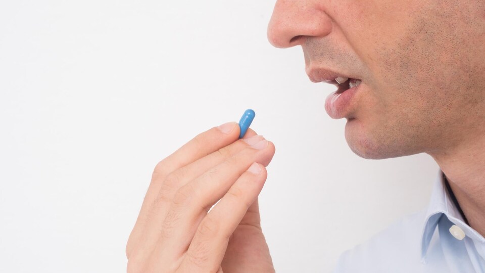 Un homme avale une pilule bleue.