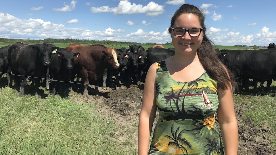 Laurie Côté Sarrazin pose devant un troupeau de bovins dans un pré.