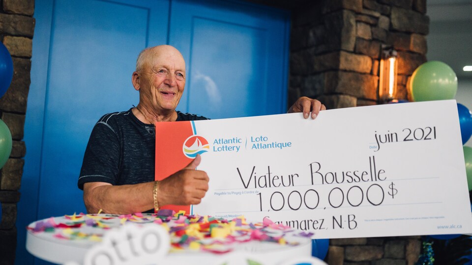 Viateur Rousselle tient un gros chèque d'un million.