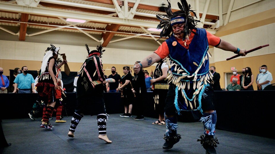 Des personnes autochtones dansent avec des habits traditionnels. 