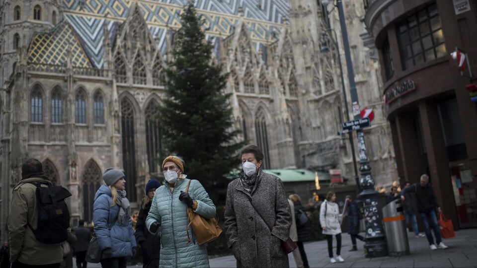 Des personnes masquées marchent devant la cathédrale Saint-Étienne, à Vienne.