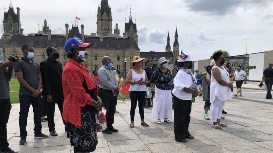 Des personnes sont réunies devant l'édifice du Parlement à Ottawa.