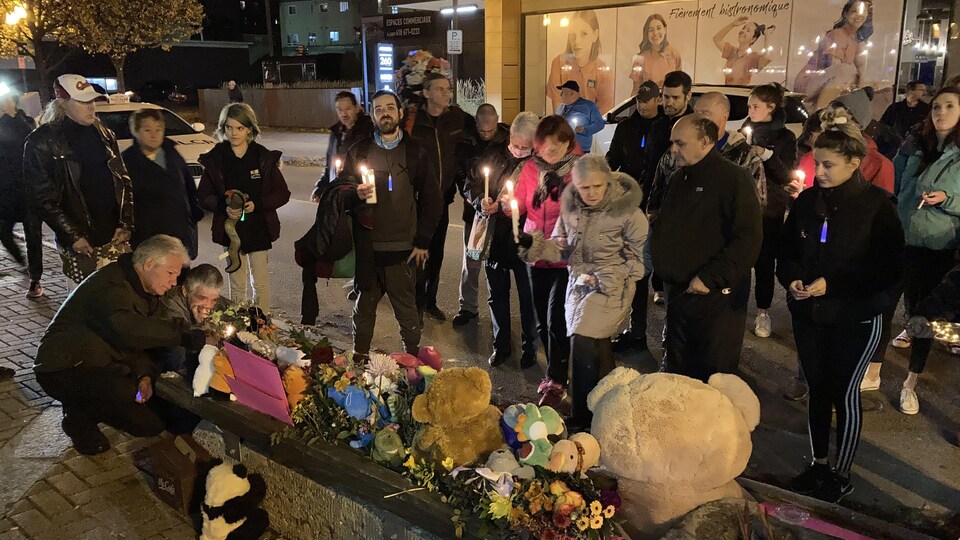 Des gens se recueillent autour d'un mémorial avec des toutous.