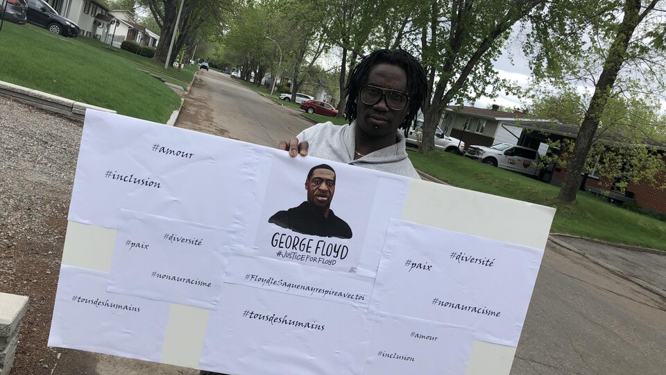 Marcellin Gbazai tient une pancarte avec une photo de Georges Floyd.