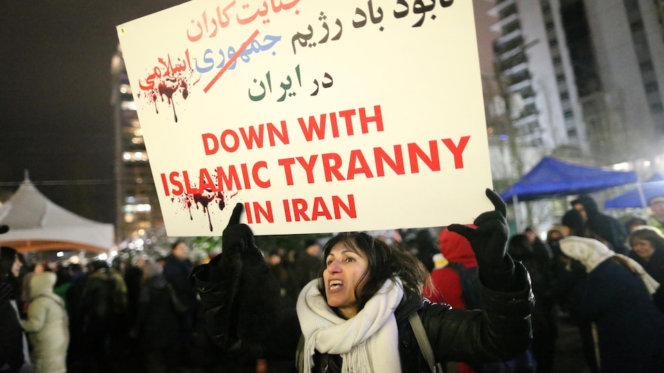 Une femme brandit une pancarte au milieu d'une foule. 