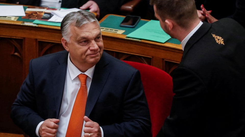 Viktor Orban, assis, parle avec un homme qui se tient debout. 