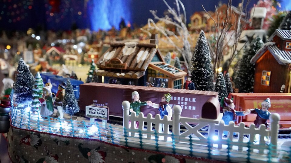 Des petits personnages se donnent la main sur le trottoir d'un village de Noël miniature.                               