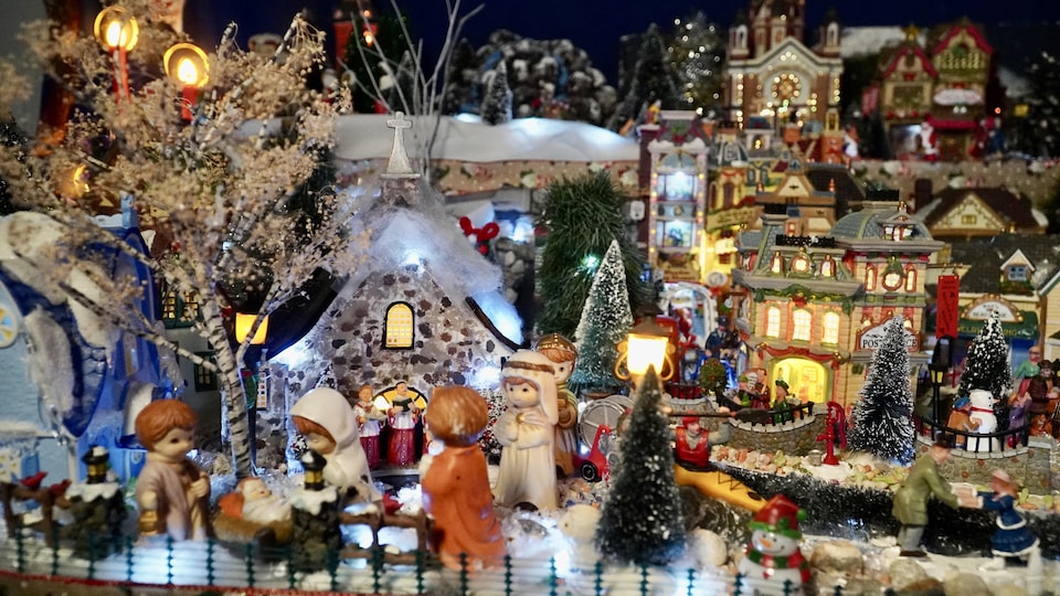 De petits personnages forment la crèche devant une église dans un village miniature de Noël.                                