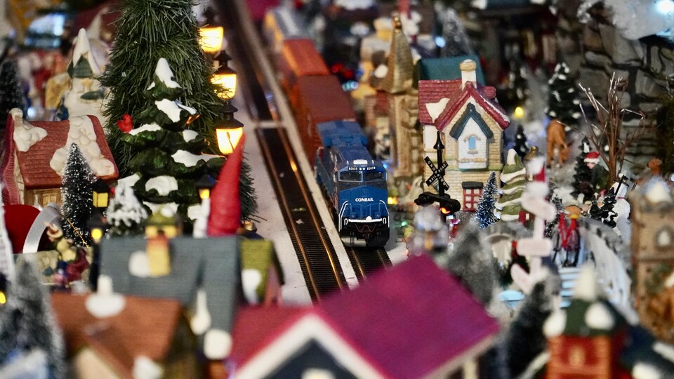 Un train miniature traverse un village de Noël.                               