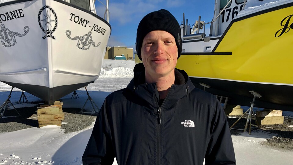Vincent Gallagher-Duguay regarde la caméra, debout devant des bateaux dans la neige.