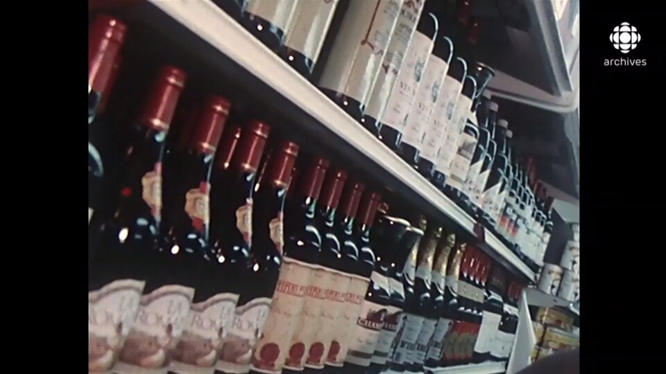 Des bouteilles de vin sont alignées sur plusieurs étagères d'une épicerie.